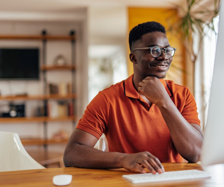 Man at desk looking very pleased with what he is reviewing on his desktop computer.