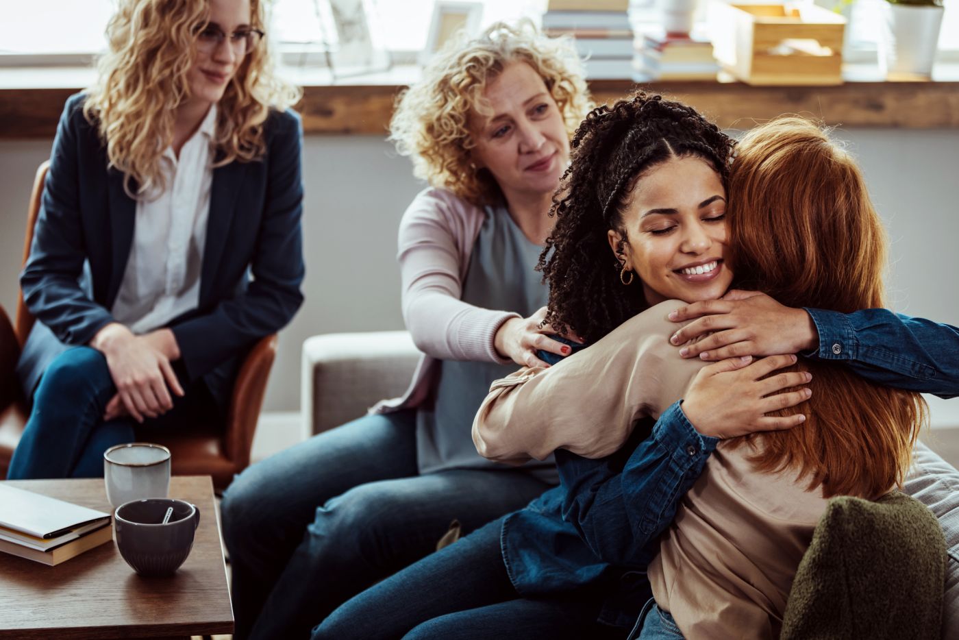 A woman supportively hugging another woman in a group setting